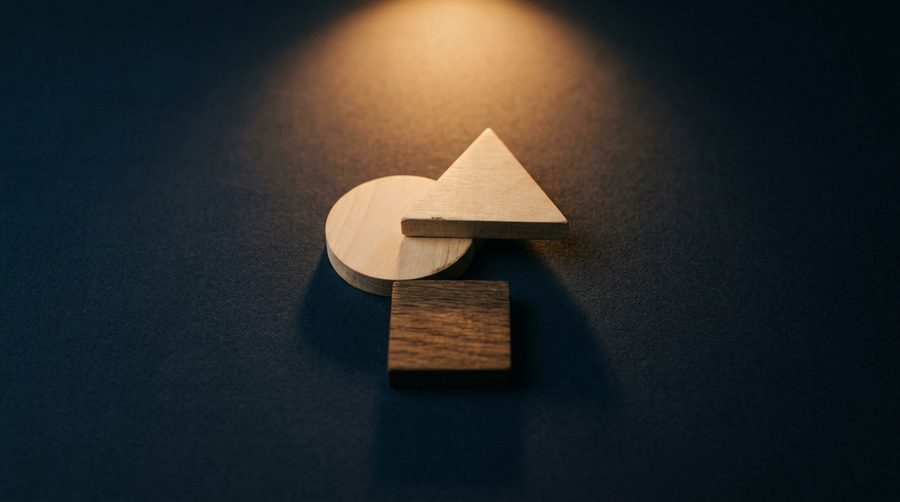Susunan bentuk geometris kayu lingkaran segitiga dan persegi menjadi komposisi lambang di atas permukaan biru gelap dengan sorotan amber